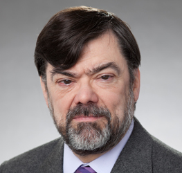 Man with dark hair and beard wearing a grey suit jacket, lavender shirt, and tie, posing in front of a neutral grey background—ideal for professionals in intellectual property law or Chicago lawyers seeking impactful profiles.