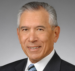 A man with short gray hair in a dark suit, white shirt, and striped tie, poses confidently in front of a plain gray background—reflecting the professionalism of top lawyers in Chicago specializing in intellectual property law.