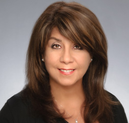 Portrait of a woman with shoulder-length brown hair, wearing a black top, smiling confidently—an excellent representation of successful Chicago lawyers—posing against a plain gray background.