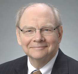 An older man wearing glasses, a dark pinstripe suit, a white shirt, and a patterned tie smiles at the camera against a plain gray background, embodying the professionalism of top law offices specializing in litigation support.