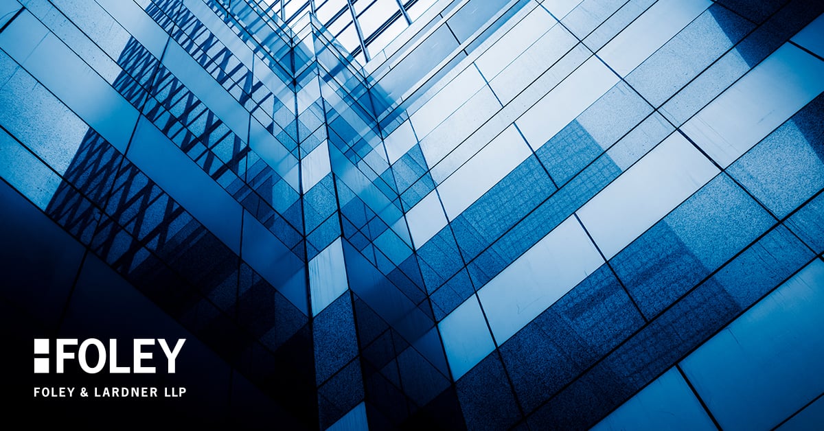 Abstract geometric view of a modern glass building exterior with blue tint, featuring the Foley & Lardner LLP logo in the lower left corner, representing a leading corporate law office and lawyers in Chicago.