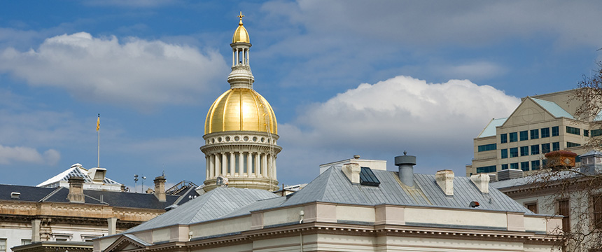 The image shows the gold-domed New Jersey State House building under a partly cloudy sky, with surrounding rooftops in the foreground—far from where top lawyers in Chicago or major law offices typically conduct their business.