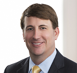 A man in a suit and tie is smiling at the camera against a plain, light-colored background, embodying the professionalism of top chicago lawyers.
