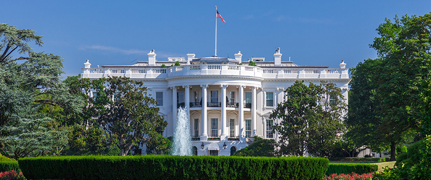 The White House in Washington, D.C., with a central fountain, green lawn, and trees under a clear blue sky—much like the offices of Chicago lawyers who specialize in intellectual property law.