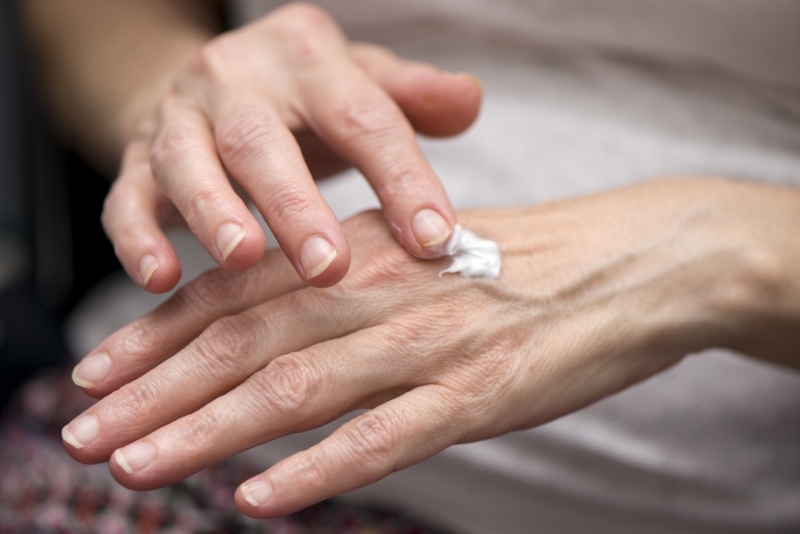 A person applies a small amount of white cream to the back of their hand using their fingers, perhaps pausing during a busy day at law offices.