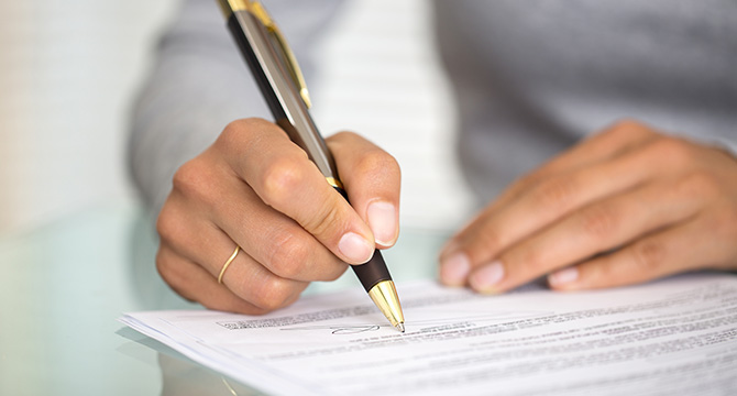 A person holding a pen signs a document on a glass table, with focus on the hand and signature area—depicting how chicago lawyers provide crucial litigation support for their clients.