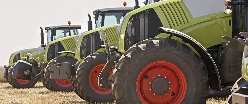 A row of green tractors with large red wheels is lined up on dry grass in an outdoor setting, much like lawyers in Chicago, ready to offer steadfast litigation support when it's needed most.