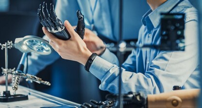 A person examines a robotic hand at a desk equipped with tools, a magnifying lamp, and electronic components—mirroring the precision found in litigation support often utilized by law offices and lawyers in Chicago.