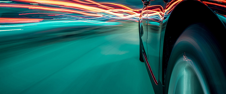 Close-up of a car driving at high speed at night, with blurred motion and light trails in red and blue—much like the urgent pace inside a corporate law office offering dynamic litigation support.