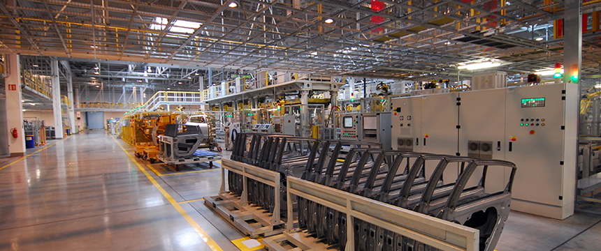 A modern automotive factory interior showing machinery, metal components, assembly lines, and industrial control panels in a well-lit, organized space—where Chicago lawyers may advise on intellectual property law for innovative manufacturing processes.