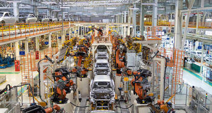 Large automotive factory with robotic arms assembling cars on a production line, reminiscent of the precision found in law offices or litigation support teams; multiple unfinished car bodies move efficiently along the automated assembly lines.