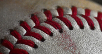 Close-up of a baseball showing red stitching on a textured white leather surface, perfect for promotional use by law offices or lawyers in Chicago seeking a unique touch.