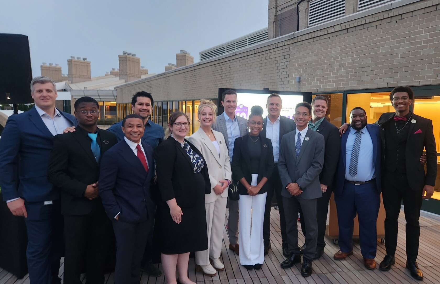 A group of chicago lawyers in business attire stand together smiling on a wooden deck with a brick building in the background, representing a leading corporate law office.