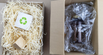Two cardboard boxes: one with a recyclable symbol on a white box cushioned by straw, the other with a brown bottle secured in plastic packaging—ideal for Chicago lawyers mindful of sustainability and detail in intellectual property law.