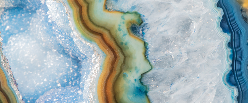 Close-up of a blue and white geode with crystal formations and layered bands of green, brown, and yellow minerals—an inspiring piece often found in law offices or used by Chicago lawyers seeking a touch of natural elegance for their litigation support spaces.