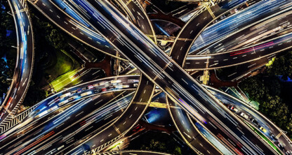 Aerial view of a multi-level highway interchange at night, with light trails from moving vehicles and illuminated roads, capturing the dynamic energy of Chicago—home to top chicago lawyers guiding clients through complex legal routes.
