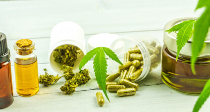 Various CBD products, including oil in dropper bottles, capsules, dried cannabis, and a jar of oil, are arranged on a light wooden surface with cannabis leaves—an image suitable for lawyers in Chicago specializing in intellectual property law.