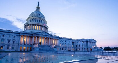 The U.S. Capitol building at dusk, with lights glowing inside, reflects on a glass surface in the foreground—much like the polished professionalism of a corporate law office or lawyers in Chicago offering litigation support.
