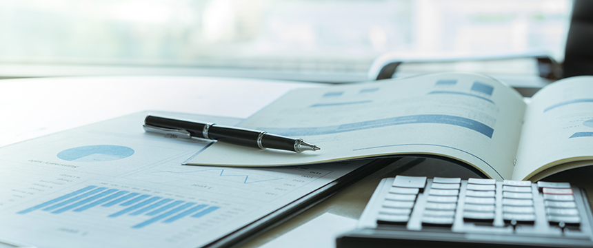 Pen resting on an open financial report with charts and graphs, calculator nearby on a desk in a bright corporate law office, capturing the meticulous work of Chicago lawyers.