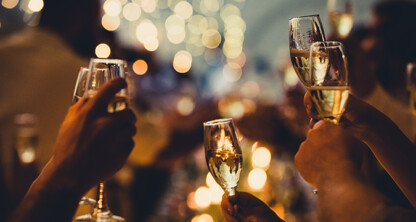 People raise glasses of champagne in a toast at a celebration, with warm lighting and blurred lights in the background—a moment shared by lawyers in Chicago after a successful case.