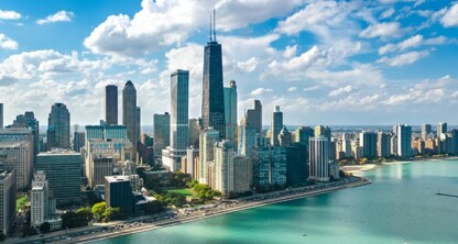 Aerial view of a city skyline with tall buildings, including prominent law offices, next to a large body of water under a partly cloudy sky.