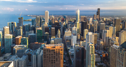 Aerial view of downtown Chicago with tall skyscrapers, law offices clustered throughout the city, Lake Michigan in the background, and partly cloudy skies.