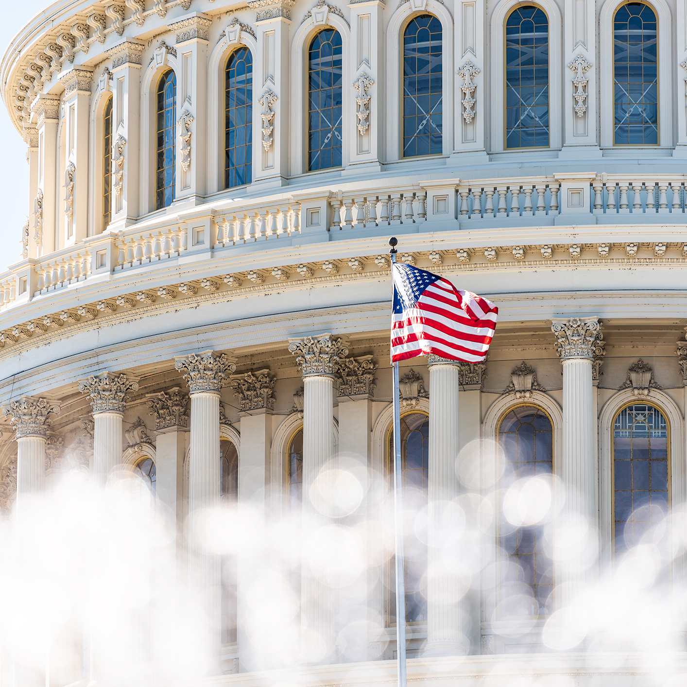 The American flag waves in front of the United States Capitol building, home to decisions impacting corporate law offices and shaping the nation’s approach to litigation support. Architectural details and stately columns are visible.
