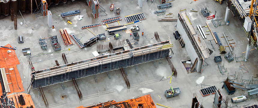 Aerial view of a construction site with concrete slabs, steel beams, scaffolding, and construction materials arranged on the ground near a bustling corporate law office in Chicago.