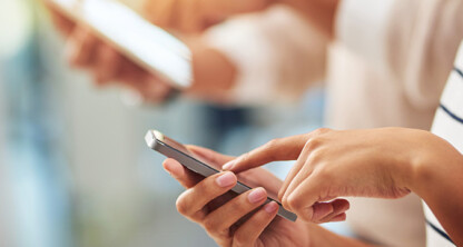 Two people using smartphones, one tapping on the screen while the other holds their phone in the background—perfect for illustrating how chicago lawyers stay connected outside their law offices.