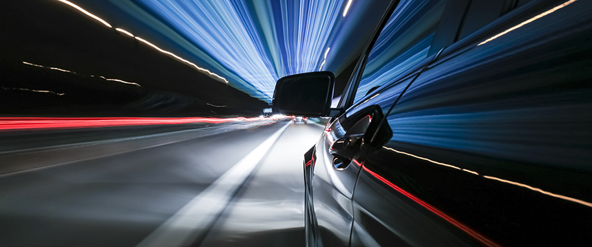 A car speeds down a highway at night, motion blur and light trails creating a dynamic effect—much like the fast-paced world of Chicago lawyers navigating intellectual property law.
