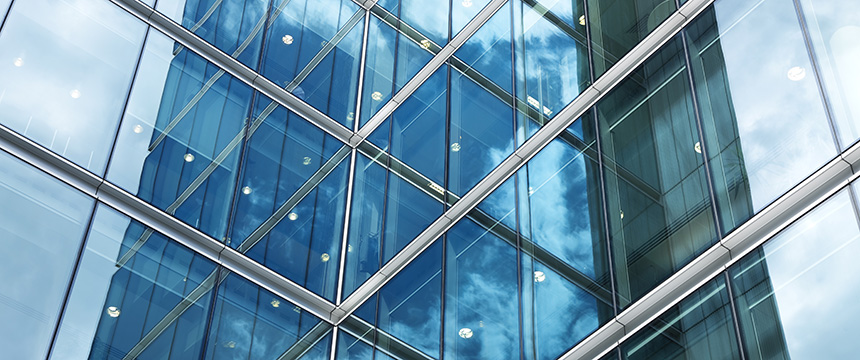 Close-up view of a modern glass office building facade reflecting blue sky and clouds, with geometric lines and window frames intersecting—an inspiring scene where top Chicago lawyers provide expert litigation support.