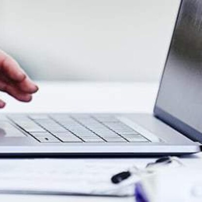Person typing on a laptop at a white desk with a clipboard and papers nearby in a bright, modern corporate law office, ideal for litigation support and lawyers in Chicago.