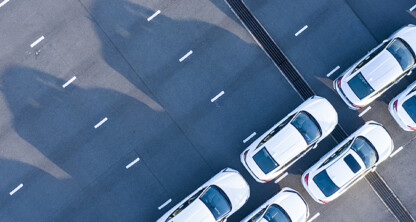 Aerial view of several white cars parked diagonally in organized rows on an empty, multi-lane road—an orderly scene reminiscent of a corporate law office parking lot for Chicago lawyers.