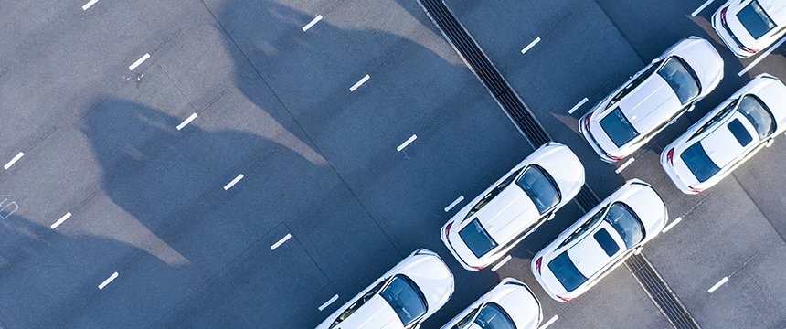 Aerial view of several white cars parked diagonally in organized rows on an empty, multi-lane road—an orderly scene reminiscent of a corporate law office parking lot for Chicago lawyers.
