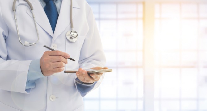 A doctor in a white coat uses a stylus and tablet, a stethoscope around their neck, with a bright window in the background—mirroring the professionalism found in leading corporate law offices or among top lawyers in Chicago.