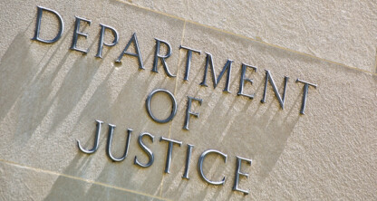 A stone wall with the words "DEPARTMENT OF JUSTICE" in metal letters, reminiscent of the entrance to prestigious law offices or the headquarters of top lawyers in Chicago.