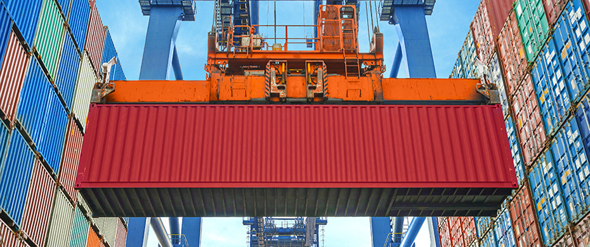A large red shipping container is being lifted by an orange crane at a shipping port, surrounded by stacked colorful containers—much like law offices in Chicago navigating complex logistics with expert litigation support.