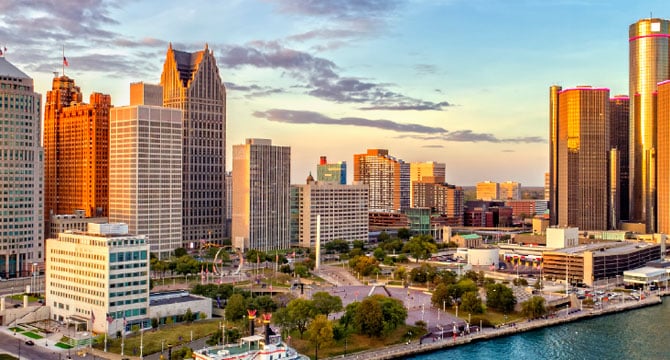 Aerial view of downtown Detroit, Michigan, with high-rise buildings, green spaces, and the riverfront at sunset—an inspiring cityscape often mirrored in the bustling energy of corporate law offices or lawyers in Chicago just across the lake.