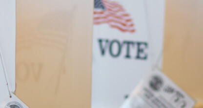 Row of voting booths with American flags and the word "VOTE" displayed, set up indoors for an election, similar to dedicated spaces used by lawyers in Chicago for confidential consultations or litigation support.