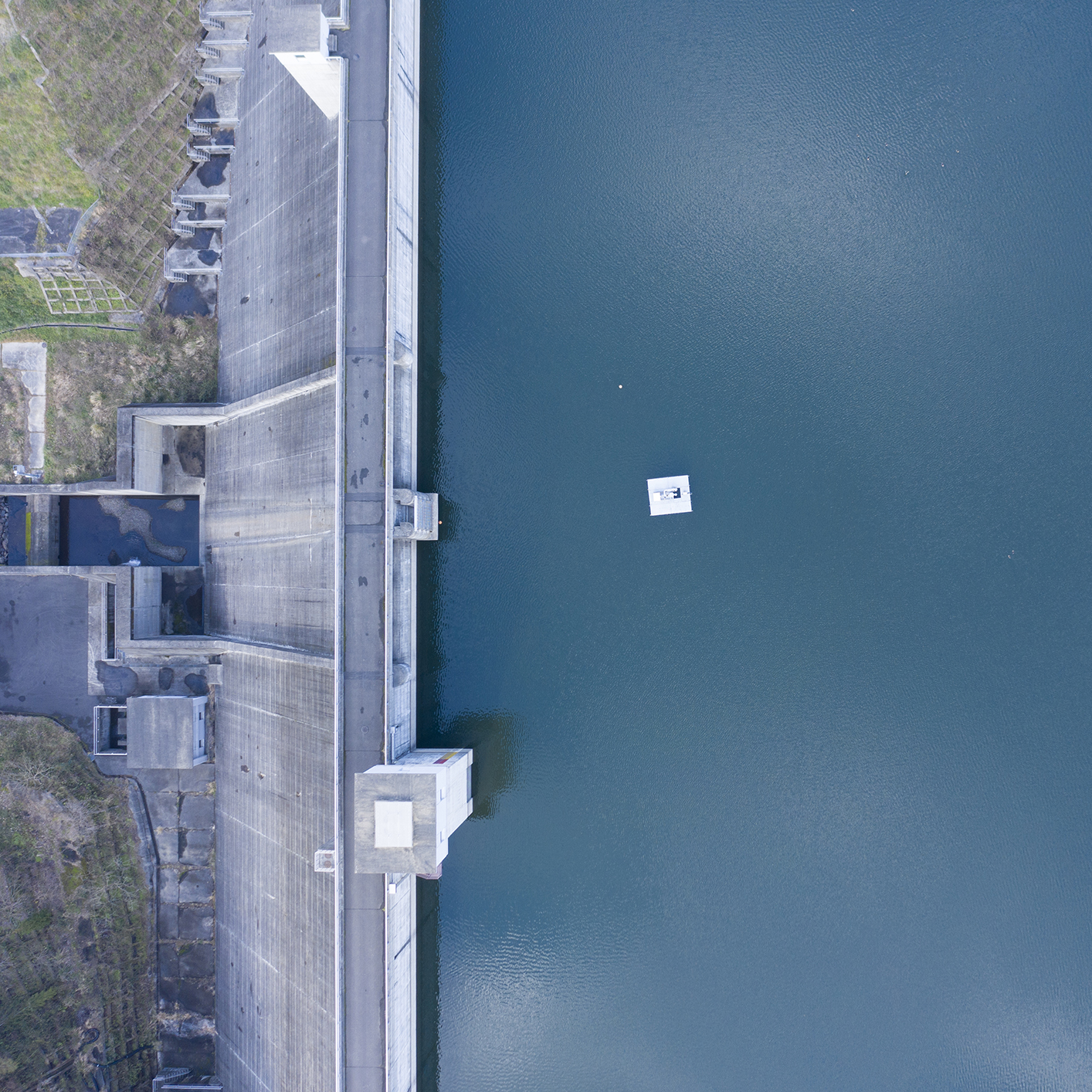 Aerial view of a concrete dam with water on one side and a small floating platform near the center, captured for a corporate law office specializing in environmental cases.