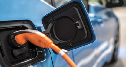 A close-up of an electric vehicle being charged, showing an orange charging cable plugged into the car's charging port—ideal imagery for lawyers in Chicago specializing in intellectual property law and emerging technologies.
