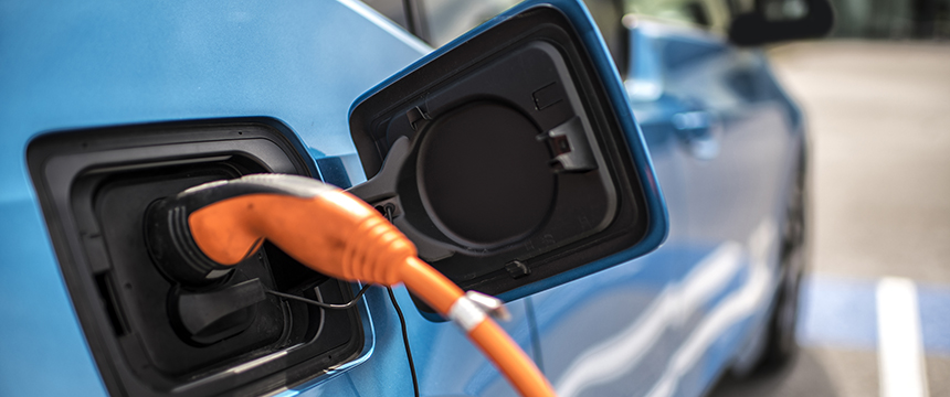 A close-up of an electric vehicle being charged, showing an orange charging cable plugged into the car's charging port—ideal imagery for lawyers in Chicago specializing in intellectual property law and emerging technologies.