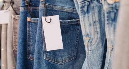 Close-up of several pairs of blue jeans hanging on a rack, each with a blank white price tag attached—perfect for lawyers in Chicago seeking casual Friday inspiration.