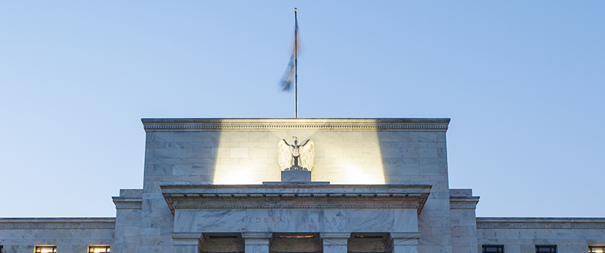 The facade of a stone building with an eagle sculpture, inscribed "Federal Reserve," and a flagpole on the roof against a clear blue sky—an iconic sight for lawyers in Chicago specializing in intellectual property law.