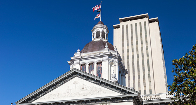 A view of the historic Florida State Capitol building with its dome, in front of the modern Capitol tower, under a clear blue sky—a striking setting for a leading corporate law office or those specializing in litigation support.