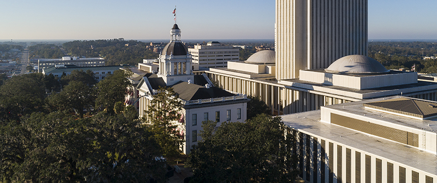 Aerial view of the Florida State Capitol complex in Tallahassee, featuring the historic capitol building with a dome and the modern high-rise capitol tower, resembling the sleek design of major corporate law offices.