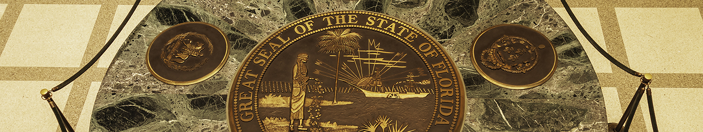 Bronze Great Seal of the State of Florida embedded in a green marble surface, surrounded by rope barriers and two smaller bronze medallions—a distinguished display often seen in prestigious law offices.