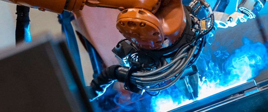 Close-up of an industrial robotic arm performing welding, with blue sparks and cables visible—much like the precision found in top corporate law offices handling complex cases.