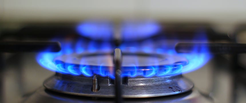 A close-up view of a lit gas stove burner with blue flames encircling the metal burner head, capturing a scene familiar to many chicago lawyers after long days of litigation support.