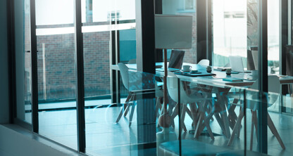 A modern conference room in Chicago law offices with glass walls, a long table, white chairs, and office supplies, empty and well-lit by natural light from large windows—perfect for meetings with lawyers in Chicago.